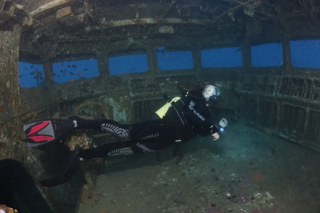 A diver swimming through the open bridge of the HMNZS Canterbury wreck